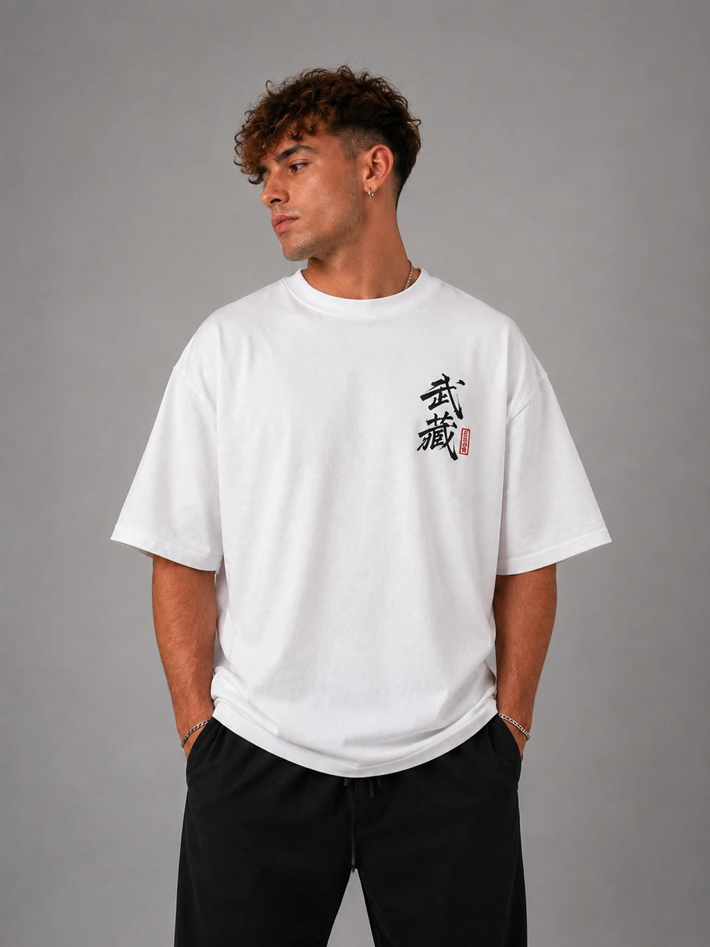 Homme portant le t-shirt oversize blanc Miyamoto Musashi de face, calligraphie japonaise de Vagabond sur la poitrine