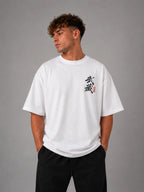 Homme portant le t-shirt oversize blanc Miyamoto Musashi de face, calligraphie japonaise de Vagabond sur la poitrine