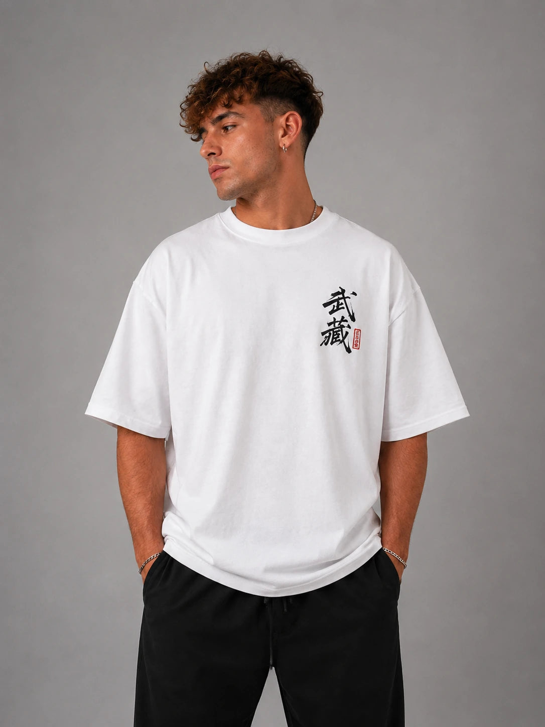 Homme portant le t-shirt oversize blanc Miyamoto Musashi de face, calligraphie japonaise de Vagabond sur la poitrine