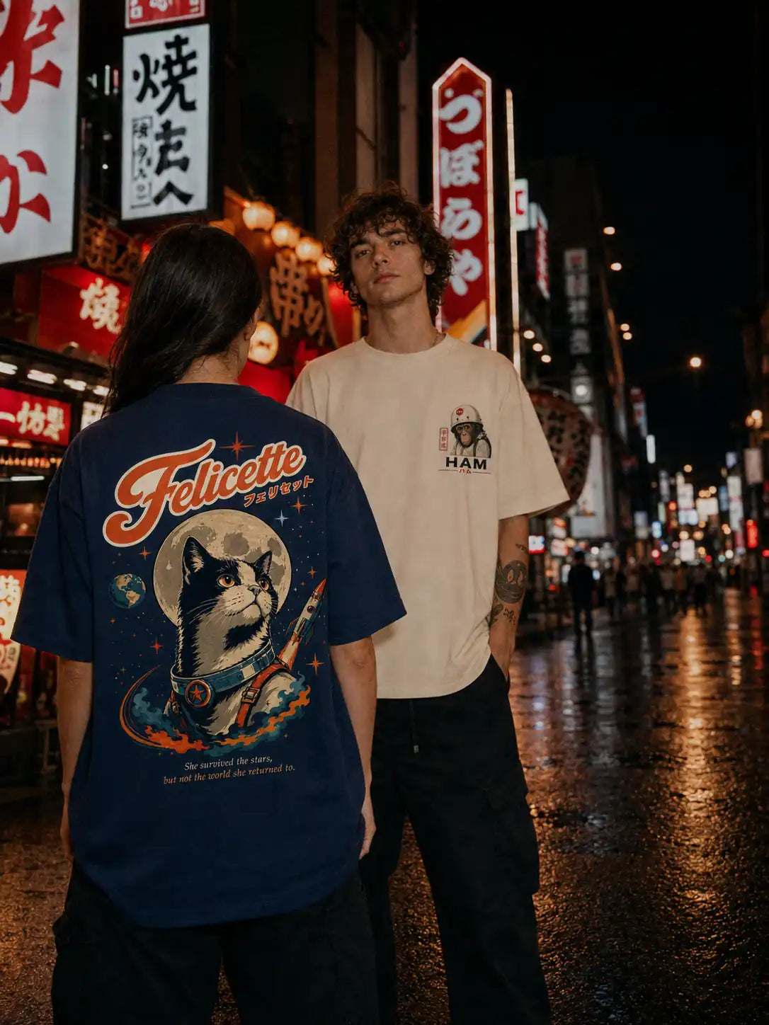 Deux modèles portant les t-shirts oversize Félicette et Ham de Benkei Studio dans une rue illuminée d'Osaka la nuit