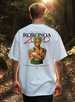 Homme marchant dans une forêt avec un t-shirt oversize blanc du manga One Piece représentant Zoro les bras croisés