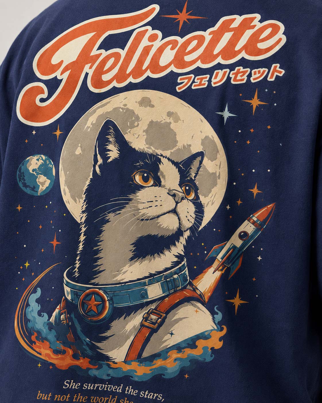 Zoom sur le dos du T-shirt Félicette : chat astronaute devant la Lune, fusée et lettrage rétro orange