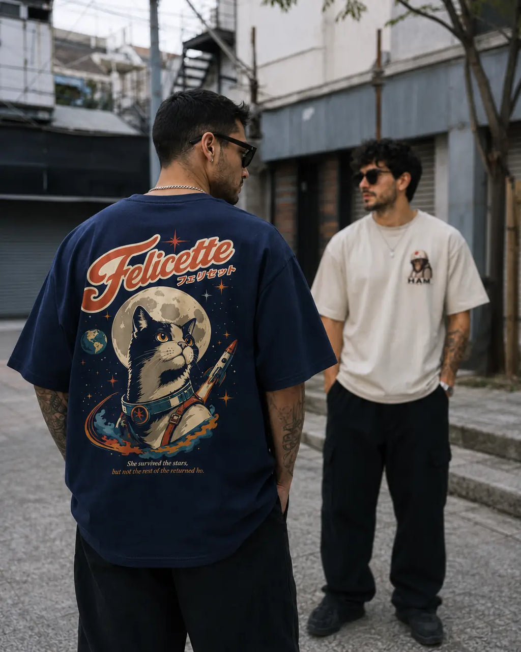Deux hommes portent les t-shirts oversize Benkei Studio Félicette bleu marine et Ham écru, collection Animaux de l'Espace