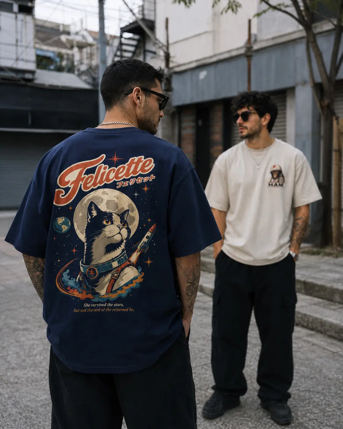 Deux hommes portent les t-shirts oversize Benkei Studio Félicette bleu marine et Ham écru, collection Animaux de l'Espace